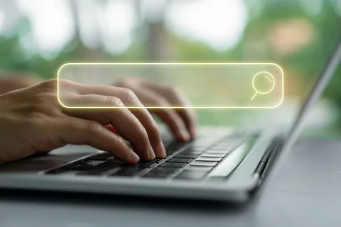Person typing a search query on a laptop representing keyword research and online search